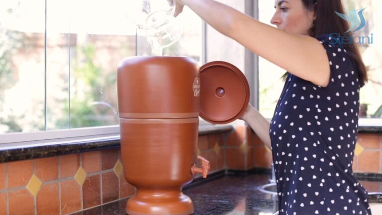 Mujer llenando el depósito superior de un filtro de agua Stéfani de cerámica.